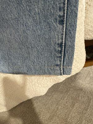 Crooked hem with one line of thread that doesn't match the jeans.