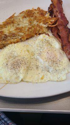 Traditional breakfast.  Fried eggs, hash browns, and bacon.