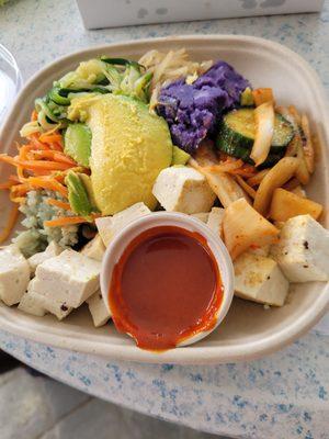 Vegetarian plate with tofu, sweet potato,  kitchen, brown rice, bamboo rice, fresh salad, avocado with special spicy sauce.