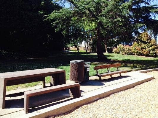 Two benches for seating and a big lawn in the back with a road that leads beyond the fence