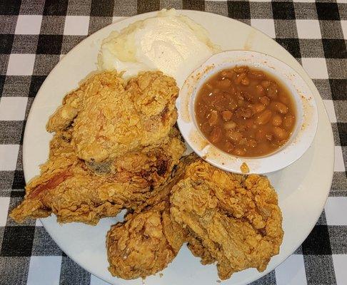 Four piece fried chicken with brown beans, mashed potatoes and gravy.