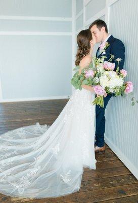 Bride leaning into groom, leaning against a wall kissing.