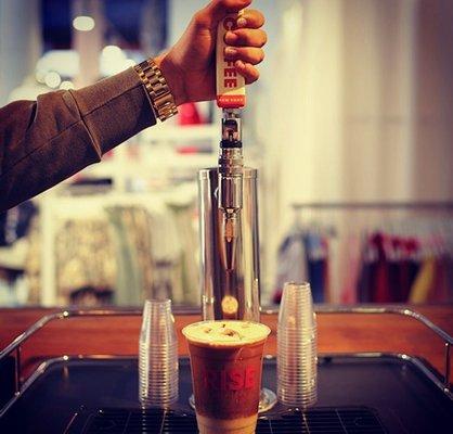 Pouring some frothy RISE Nitro Cold Brew Coffee from the tap - Our cafe is located inside The Phluid Project store