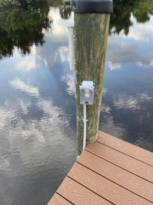 Outdoor weather resistant outlet with in-use weatherproof cover and fed from a GFCI breaker located on dock. By River Electric LLC.