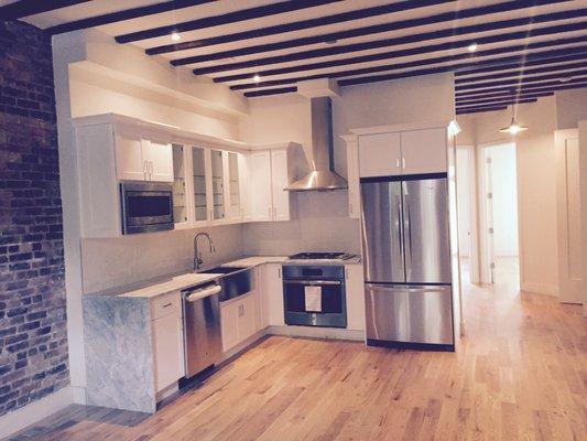 Modern White cabinets, Waterfall Countertop, Farmer Sink, Ceiling Beams, Exposed Bricks