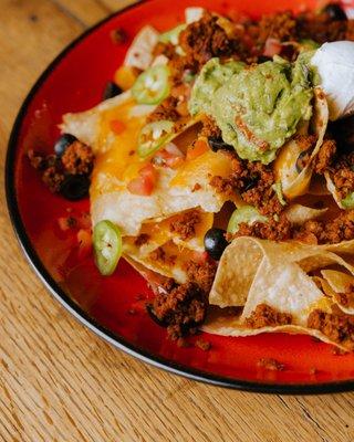 NACHOS Corn Tortilla Chips with melted pepper jack and cheddar cheese. With pico de gallo, guacamole, jalapeños, sour cream, and salsa.