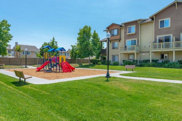 Playground with mulch, grass, and benches.