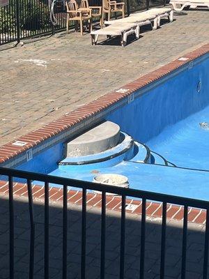 Seasonal pool with exposed concrete and rebar on the stairs