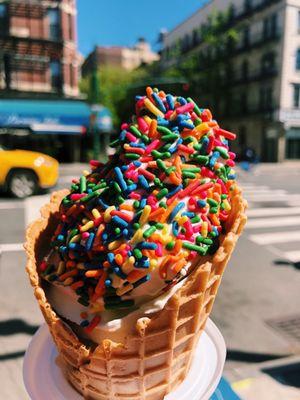 Rainbow sprinkles on soft serve and waffle cone