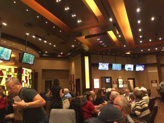 A nice poker room with a lot of tables and TVs.