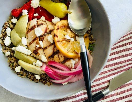 Mediterranean Quinoa Bowl with grilled chicken, artichokes, roasted peppers, pickled onions, pepperoncini, and feta cheese.