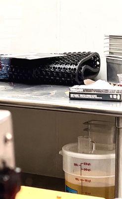 Prep area with cooking utensils and the lid to the protein bin on top of the dirty @$$ floor mat!