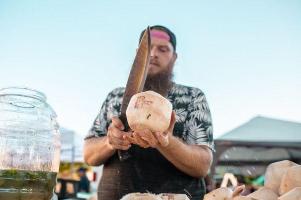 Shucking coconuts at Our Street night market. We offer coconut bartending catering for events of any size!