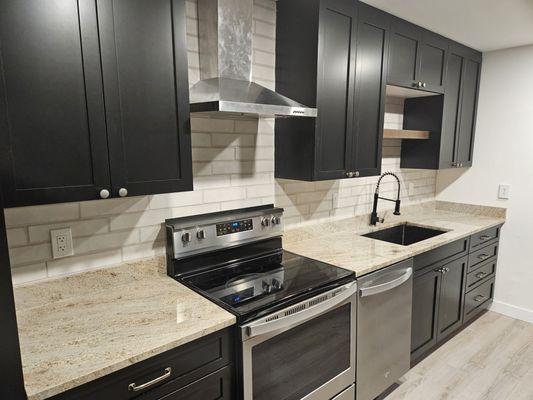 New backsplash tile, oven hood, and sink faucet.