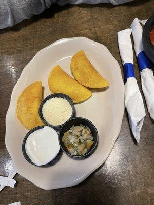 Chicken empanadas, with side of  sour cream, cheese, and dice tomatoes salad