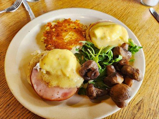 their version traditional eggs benedict w/ham with truffle sauce mushrooms, arugula, biscuit and hash brown potatoes