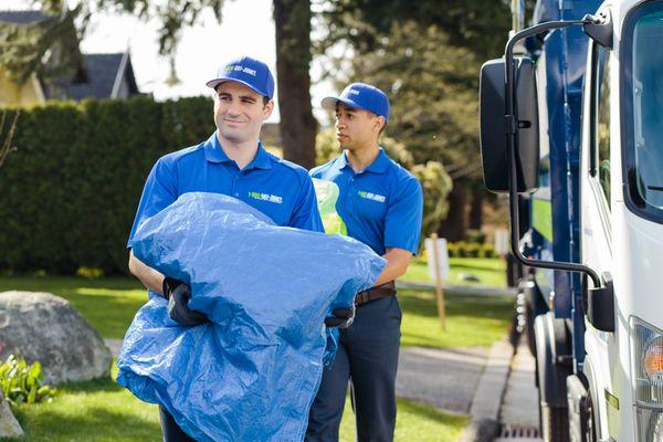 1-800-GOT-JUNK? Truck Team carrying trash bags