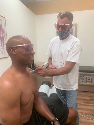 Dr. Phillip Lewis treating Byron Scott,NBA Head Coach and 3 time Champion, with laser shoulder therapy at Cool Breeze Chiropractic Center