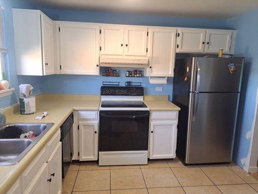 Old wooden doors and drawers dark brown sanded, primed and painted with cabinet paint to give a fresh new look in kitchen .