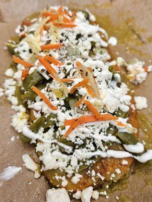 -Tlacoyos. Corn masa stuffed with cheese or beans, dipped in salsa verde, topped with cactus leaf salad, quest fresco, and crema.