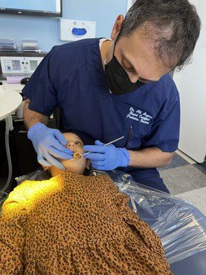 Dr. Ali gently fixing an anterior tooth on a tiny patient.