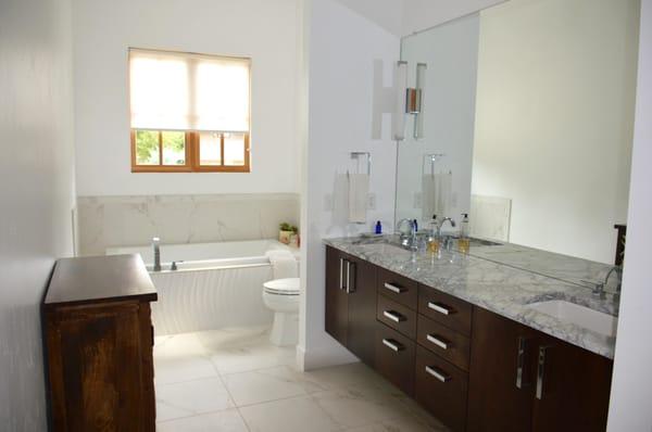 Great contrast of dark wood and white stone.  Large mirror opens up this space.