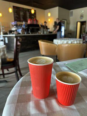 Large latte, small latte with the counter in the background.