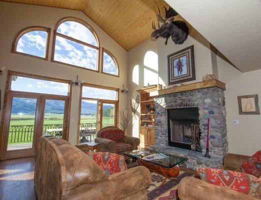 Our Great Room, featuring floor to ceiling windows and a wood burning fireplace.