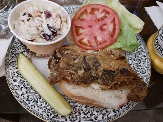 Softshell crab sandwich with lettuce and tomato, coleslaw and pickle on the side. Carryout order plated at home.