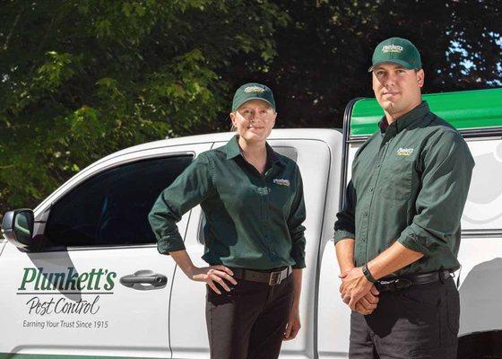 Technicians standing by service vehicle at customer residence.