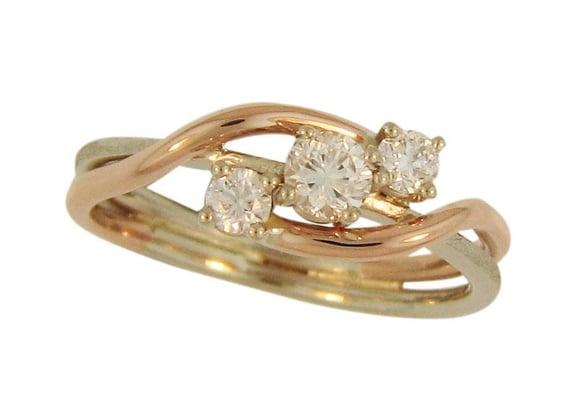 A 3-stone diamond ring hand fabricated of 14k white and rose gold.  The three diamonds weigh 0.55tdw.