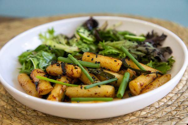 Korean savory rice cake with soy sauce served with fresh veggie salad.