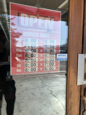 Store hours posted on their entrance door.