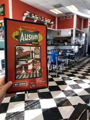 Inside the diner and holding a menu.