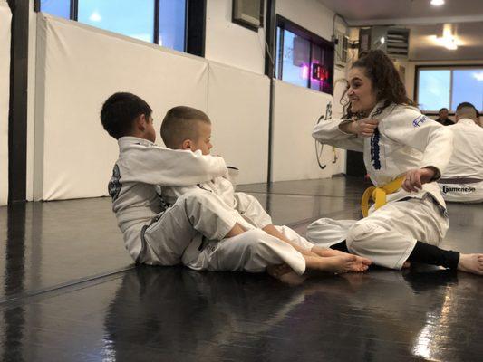 Assistant martial arts instructor (Malia) guiding students through technique during our kids martial arts class