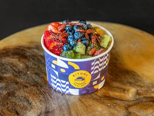 Açai topped with strawberries, mango, kiwi, blueberries, sliced almonds, granola and honey.