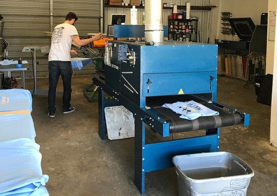 Matt screen printing t-shirts inside the shop.