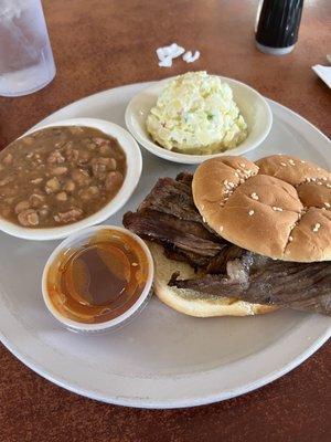 BBQ brisket sandwich with coleslaw and beans.