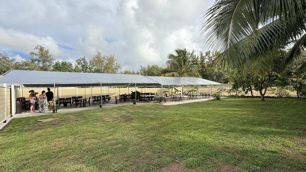 eat in a covered back yard area surrounded by grass and trees