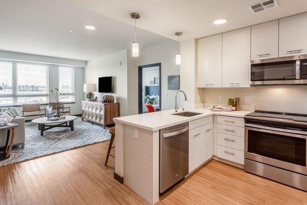 Kitchen featuring stainless-steel appliances, quartz countertops, and hardwood-style vinyl flooring.