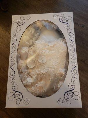 Plush dress packed inside ornate packaging with clear plastic front for viewing