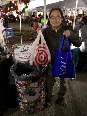 Marvin S. Kobori, D.D.S. donating canned goods to the Pacifica Resource Center Food Drive at the Rockaway Beach Tree Lighting Festival 2018