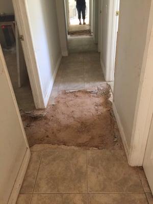 Completed sewer pipe repair and trench back filled in hallway.