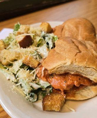 Salmon sandwich with spicy red bell pepper sauce and caesar salad. It's a delicious combination that salmon lovers must try!