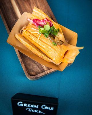 Green Chile Pork Tamales topped with cilantro, pickled red onions, roasted green chile and radish sprouts.