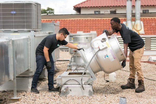 A team of Guardian Technicians inspecting and cleaning an upblast exhaust fan.