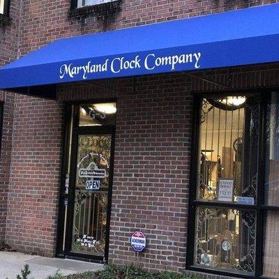 The Front door, blue awning above it with the company name Maryland Clock Company