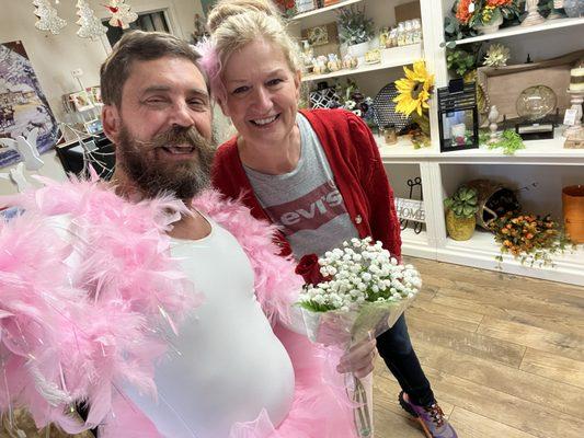 Mitch Allen posing with flowers in a pink tutu, and feather boa for losing an embarrassing bet