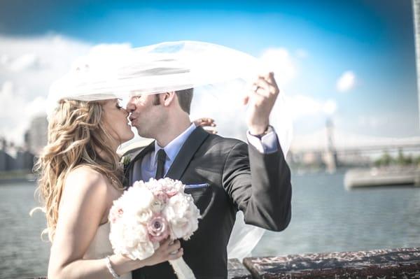 Beautiful couple kiss on a pier in Long Island City overlooking NYC.