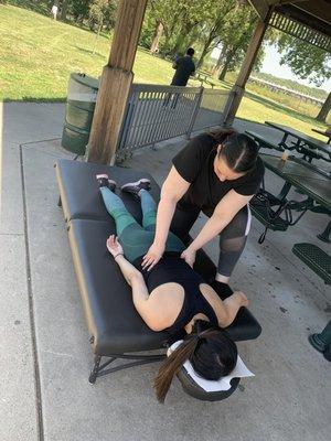 Ayra working an event attendee on a massage table they hauled out to Minnehaha Park